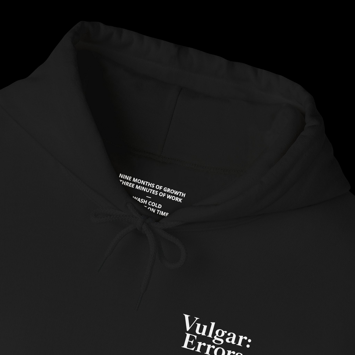 Vulgar Errors black pullover hoodie featuring a white chest logo and printed care instructions inside the neck