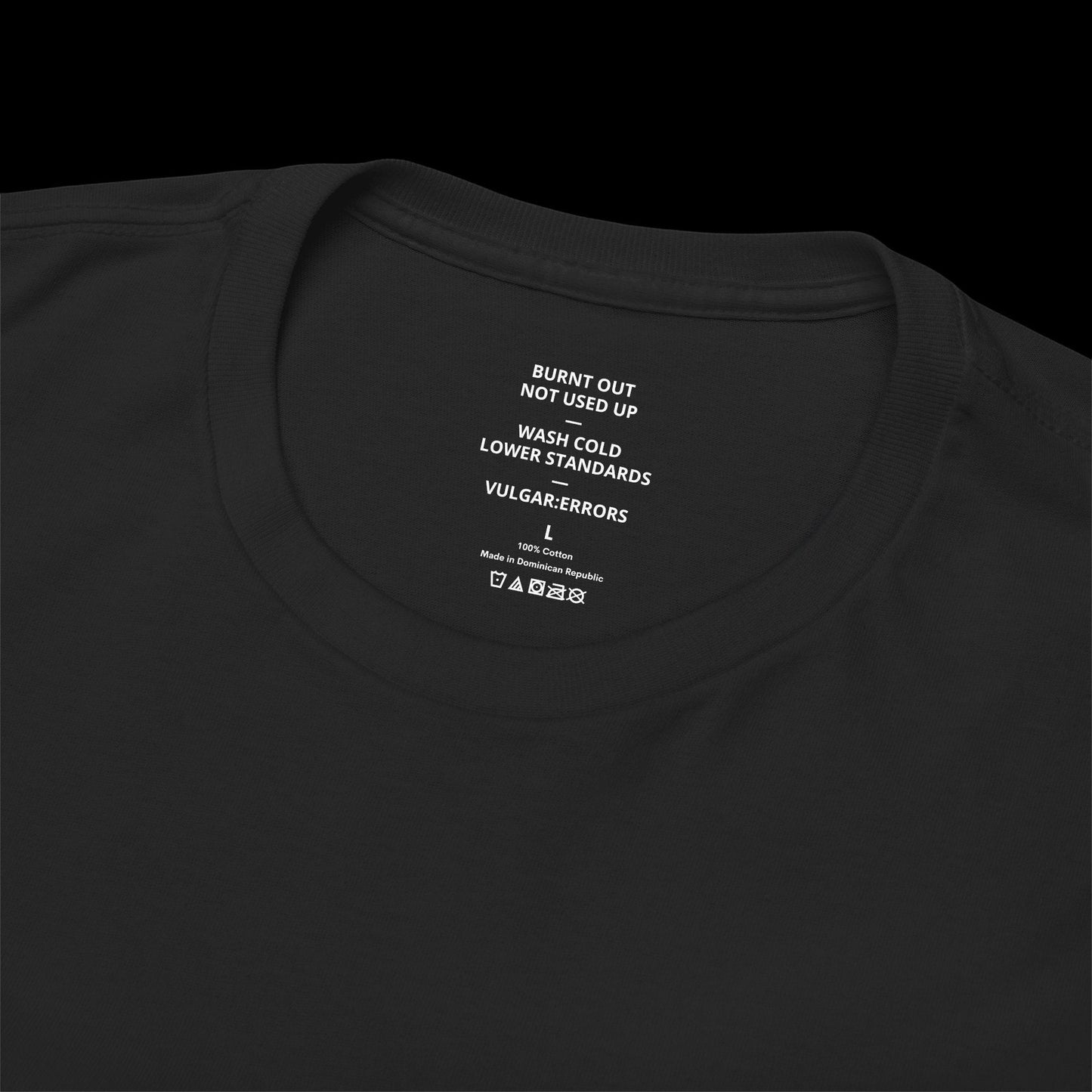 Inner neck label of the black "Burnt Out" Vulgar Errors t-shirt showing the printed care guide and size details