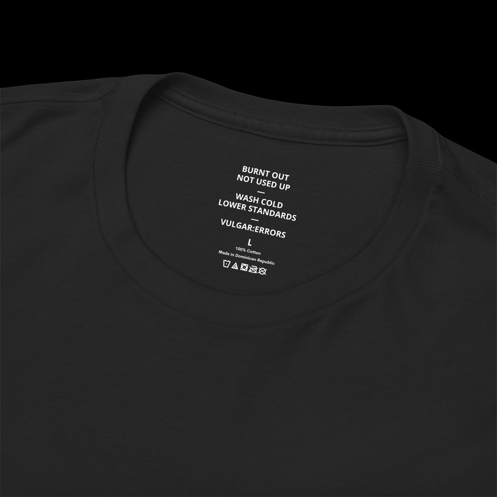 Inner neck label of the black "Burnt Out" Vulgar Errors t-shirt showing the printed care guide and size details