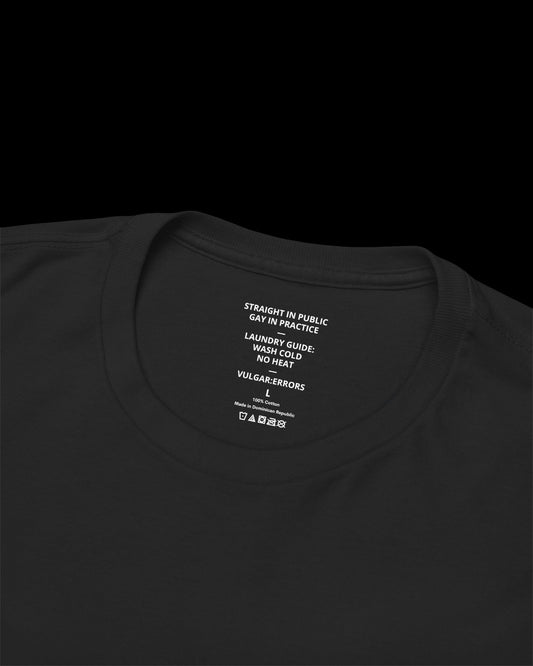 Inner neck label of black T-shirt showing printed care guide, size, and cotton fabric details