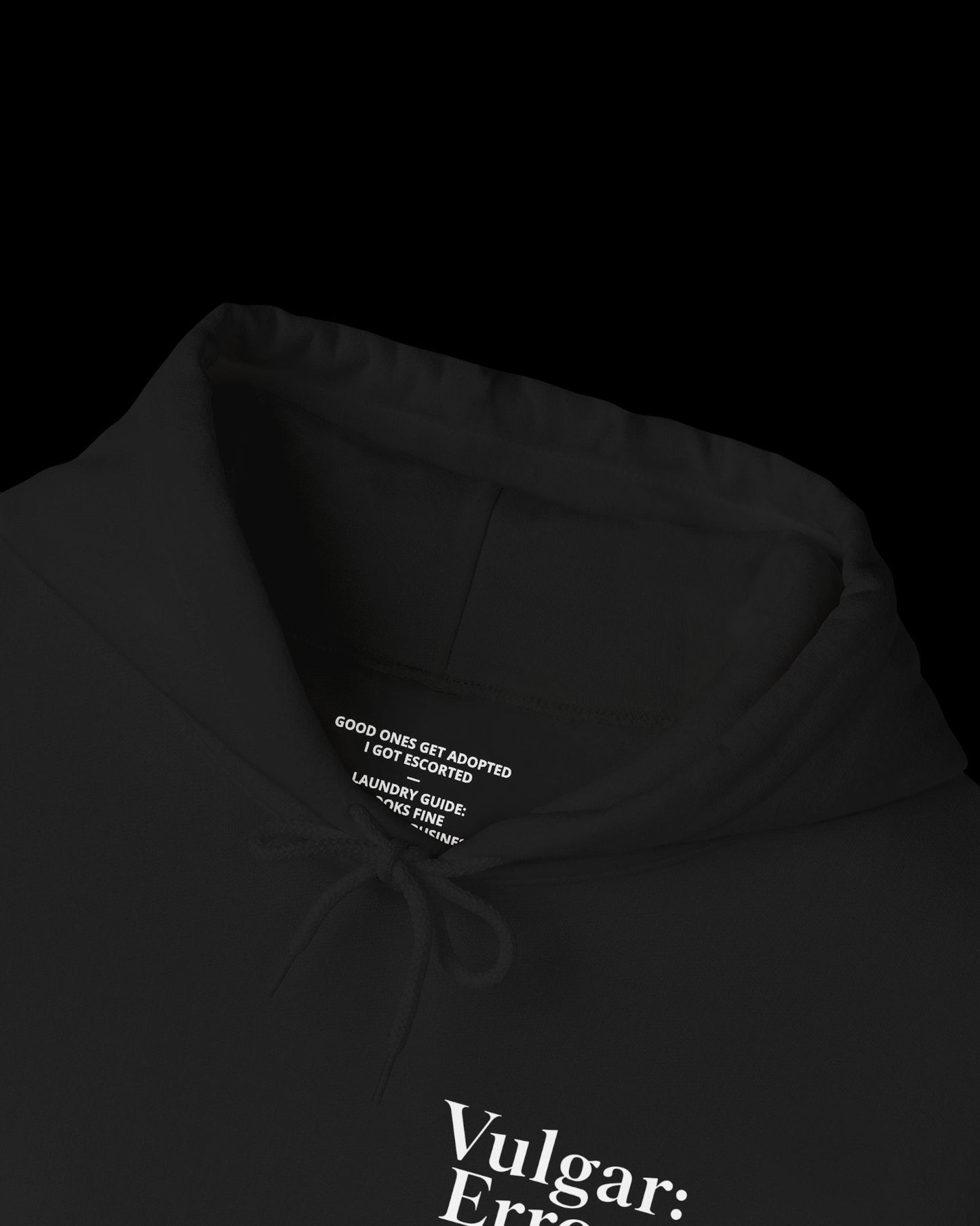 Inner neck label of black hoodie showing printed care guide, size, and cotton fabric details