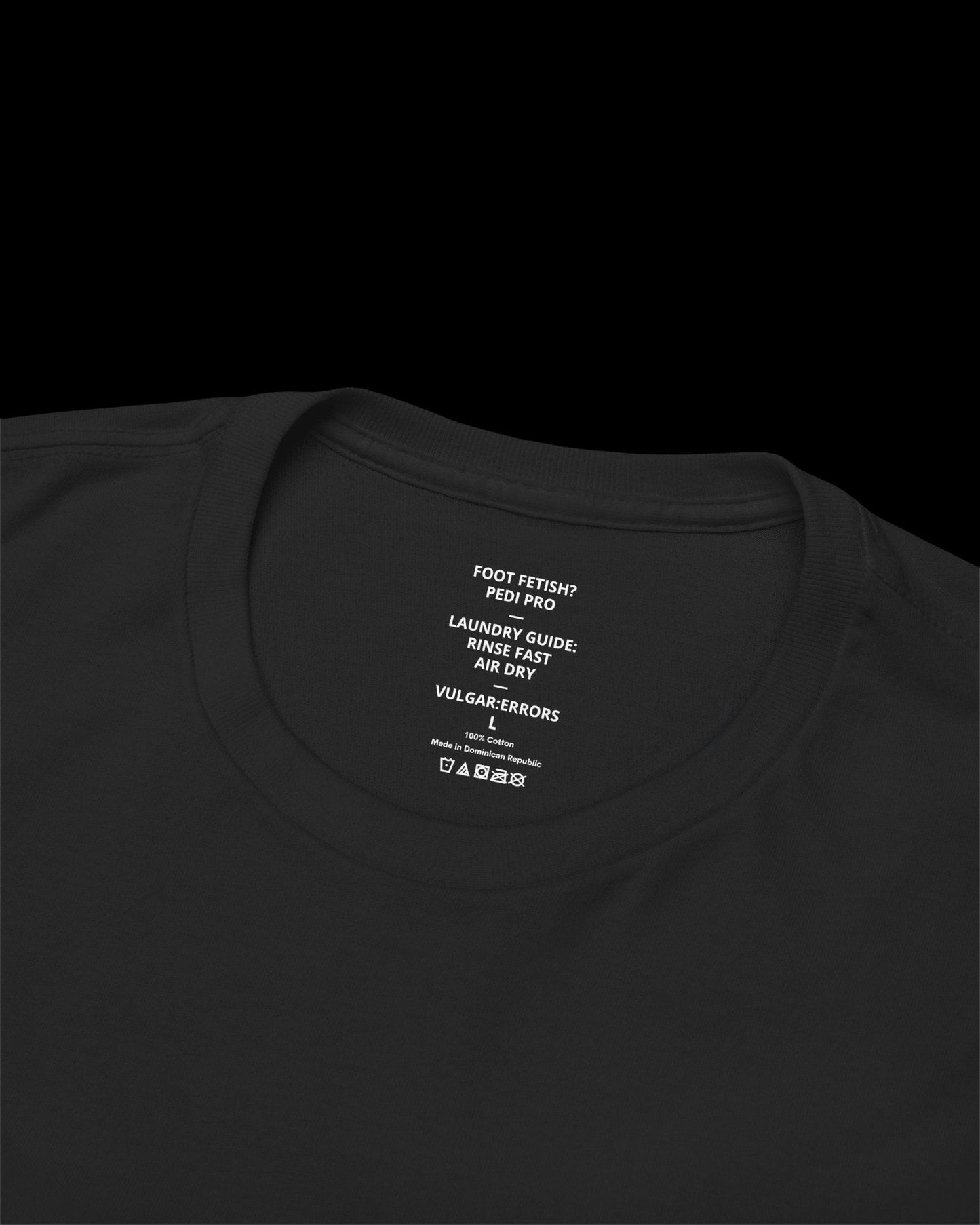 Inner neck label of black T-shirt showing printed care guide, size, and cotton fabric details