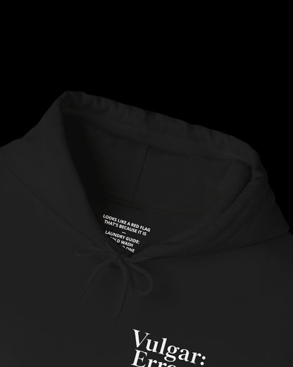 Inner neck label of black hoodie showing printed care guide, size, and cotton fabric details