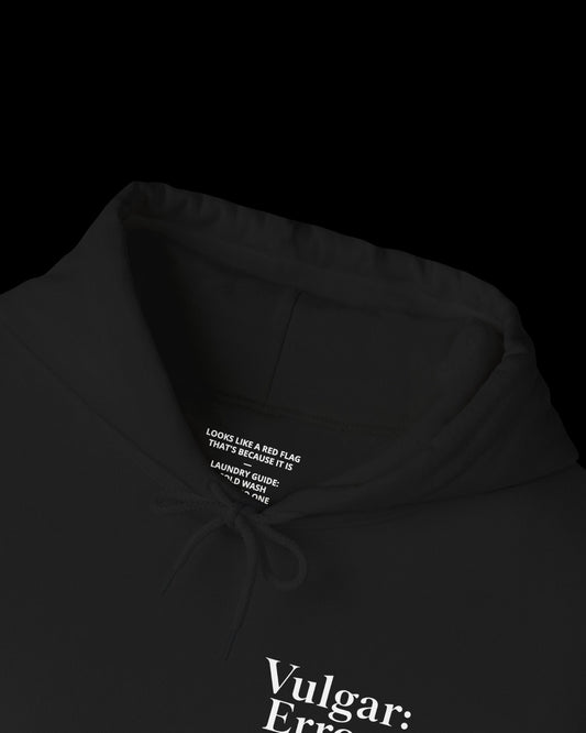 Inner neck label of black hoodie showing printed care guide, size, and cotton fabric details