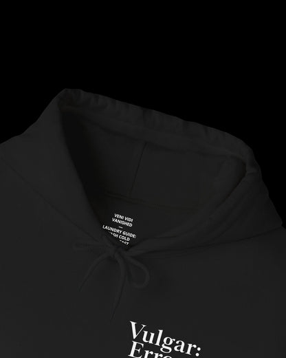 Inner neck label of black hoodie showing printed care guide, size, and cotton fabric details