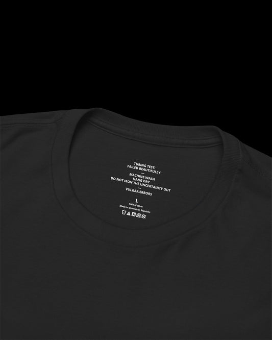 Inner neck label of black T-shirt showing printed care guide, size, and cotton fabric details