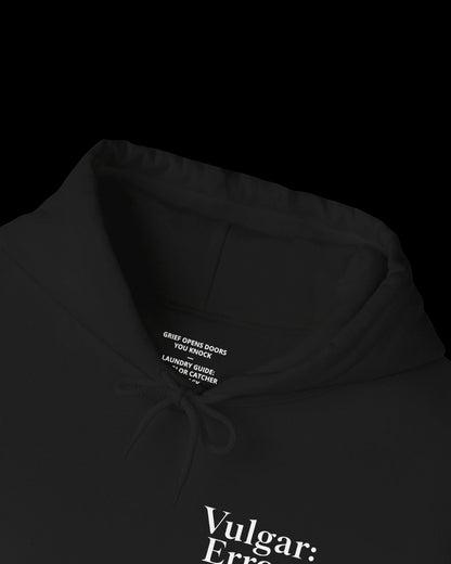 Inner neck label of black hoodie showing printed care guide, size, and cotton fabric details