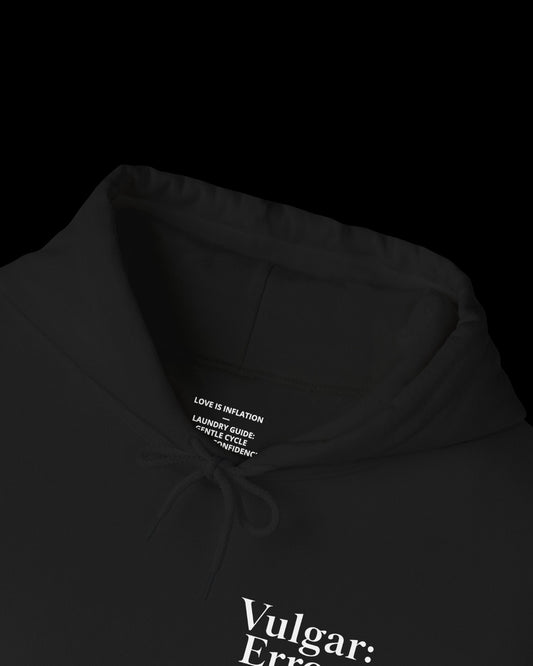 Inner neck label of black hoodie showing printed care guide, size, and cotton fabric details