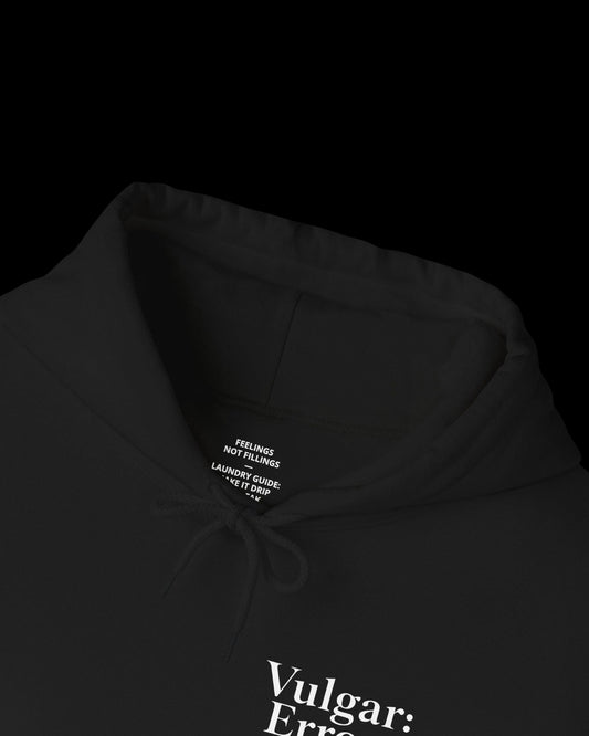 Inner neck label of black hoodie showing printed care guide, size, and cotton fabric details