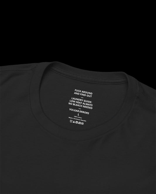 Inner neck label of black T-shirt showing printed care guide, size, and cotton fabric details
