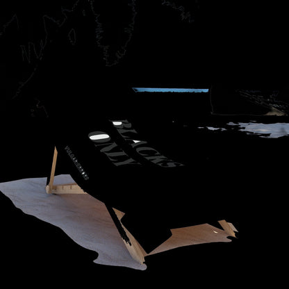 Vulgar Errors oversized black beach towel with bold white text draped over a wooden lounge chair on a sandy beach.