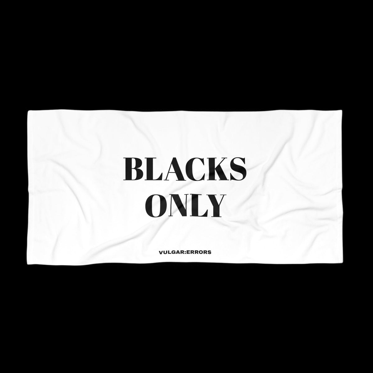 Vulgar Errors oversized white beach towel with bold black text reading BLACKS ONLY and small brand logo at the bottom
